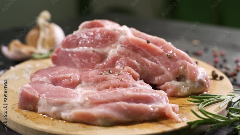 Close up side view of raw slices of fresh steak meat with falling salt on it. Close up side view of raw slices of fresh steak meat with falling salt on it.