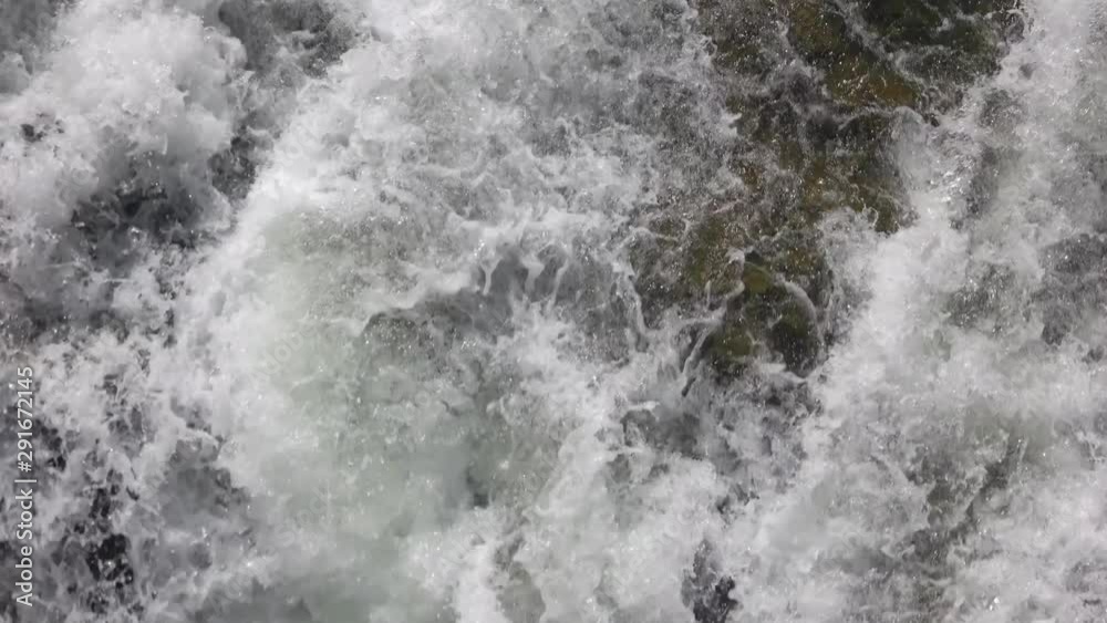 Close up of waterfall falling among stones. Close up small foamy mountain waterfall flows into river. Close up of waterfall falling among stones. Close up small foamy mountain waterfall flows into river.