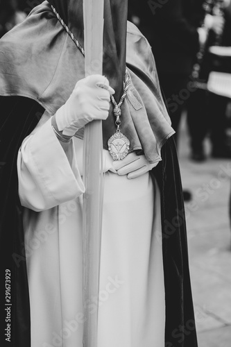 Hooded person touching belly in a procession, Holy Week