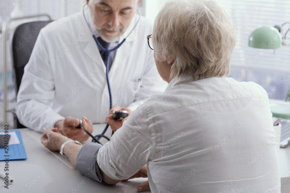 Fototapeta premium Doctor measuring blood pressure of a senior patient