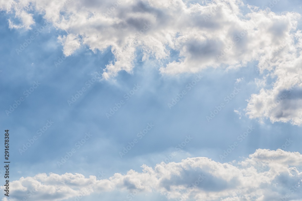 Delicate light rays through clouds on pastel blue color sky background Delicate light rays through clouds on pastel blue color sky background