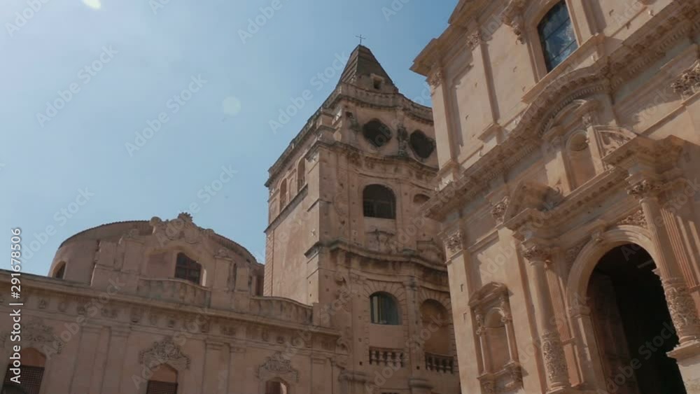 Some tourists visiting the spectacular façade of the Baroque church of S. Francesco d'Assisi and monastery of S. Salvatore in Noto, Sicily Italy. Some tourists visiting the spectacular façade of the Baroque church of S. Francesco d'Assisi and monastery of S. Salvatore in Noto, Sicily Italy.