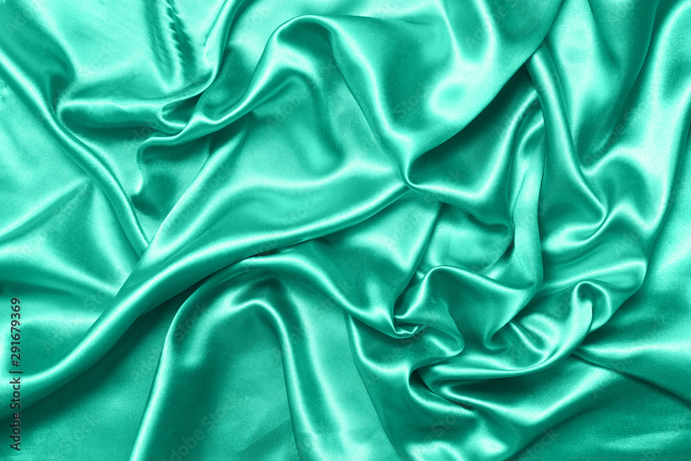 Close up of ripples on silk fabric. Satin textile background. Green color. Top view. Color of the year 2020 Close up of ripples on silk fabric. Satin textile background. Green color. Top view. Color of the year 2020