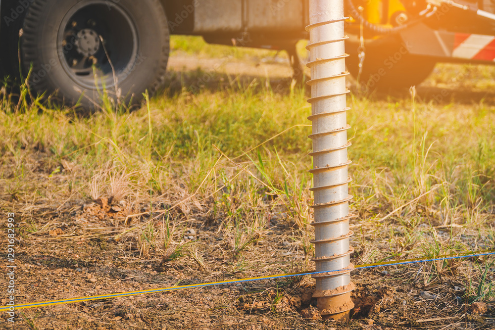 technician installing ground screw for mounting structure of solar
