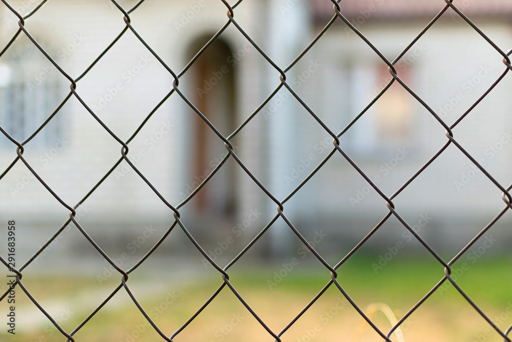 Country house in nature surrounded by a metal fence made of mesh for security against thieves and theft