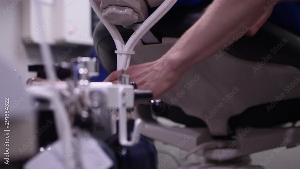 Closeup of dentist adjusting nitrous oxide tubes on dental patient ...