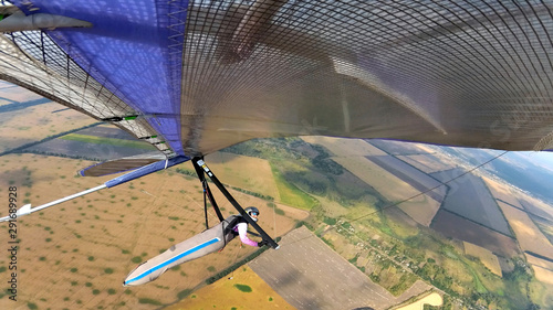 Fearless hang glider pilot fly high above terrain.