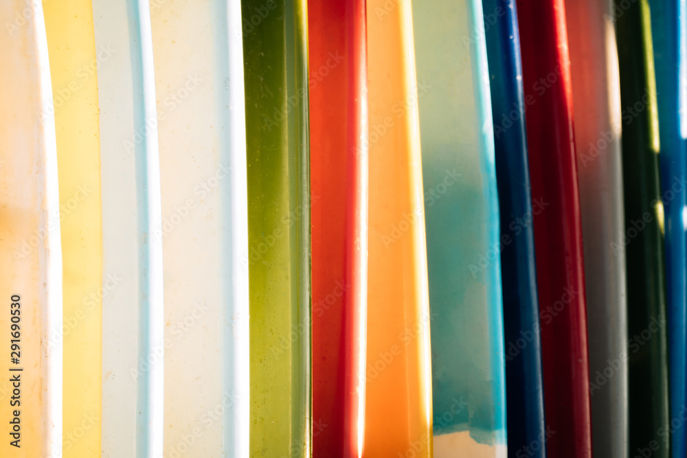 Close up Set of different color surf boards in a stack on sandy beach for rent. Multicolored surfboards as rainbow. Close up Set of different color surf boards in a stack on sandy beach for rent. Multicolored surfboards as rainbow.