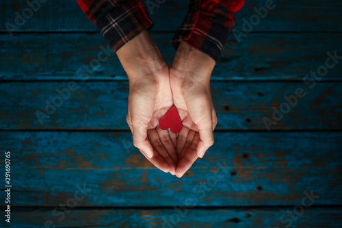 Fotografie Girl holds heart in hands on blue wooden background
