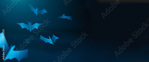 Halloween photo of blue paper bats on blank dark blue background.