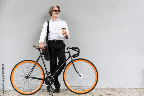 Fototapeta Naklejka Na Ścianę i Meble -  Photo of serious bearded businessman drinking coffee takeaway