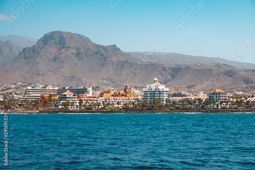 Ocean front hotels at coast view from boat on shore with mountain background -