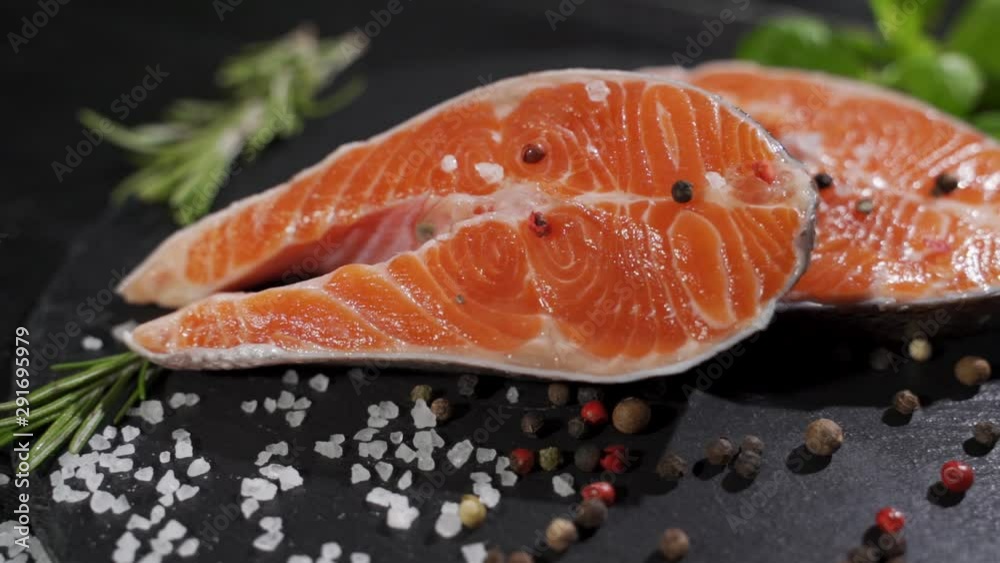 Spices fall on a raw salmon steak. Raw salmon red fish with pepper and salt. Spices fall on a raw salmon steak. Raw salmon red fish with pepper and salt.