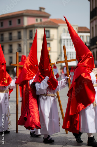 Hooded child is holding a cross in a procession, Holy Week