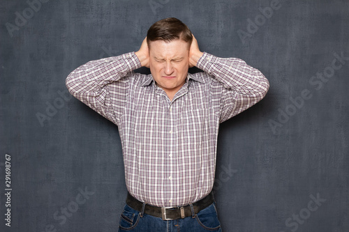 Portrait of unhappy young man covering ears with hands