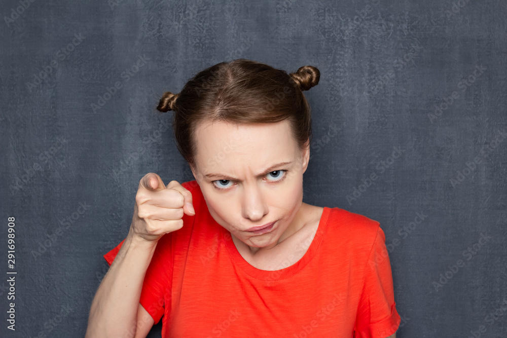 Portrait of dissatisfied girl pointing with index finger at you Portrait of dissatisfied girl pointing with index finger at you