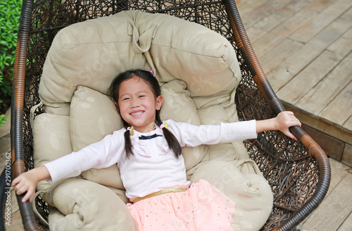 Foto Smiling Asian little child girl lying on sofa in the garden.