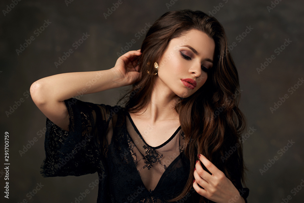 Closeup fashion studio portrait of young beautiful sensual woman with brunette wavy hair and makeup