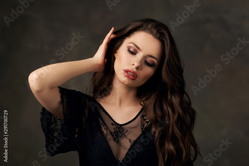 Closeup fashion studio portrait of young beautiful sensual woman with brunette wavy hair and makeup