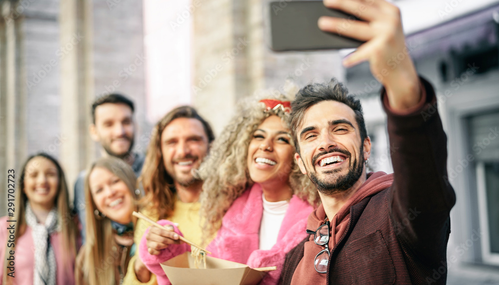 Obraz premium Group of multiracial friends eating Asian street food and taking selfie outdoor - Young trendy people having fun with new mobile smartphone apps while having a meal outside - Tech and social concept