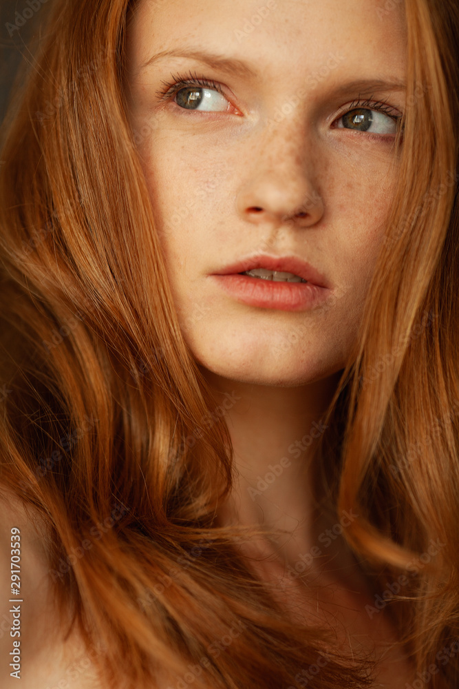 Natural female beauty concept. Emotive portrait of thinking model with red (ginger) wavy hair and natural make-up. Perfect skin with freckles. Retro style. Close up. Studio shot Natural female beauty concept. Emotive portrait of thinking model with red (ginger) wavy hair and natural make-up. Perfect skin with freckles. Retro style. Close up. Studio shot