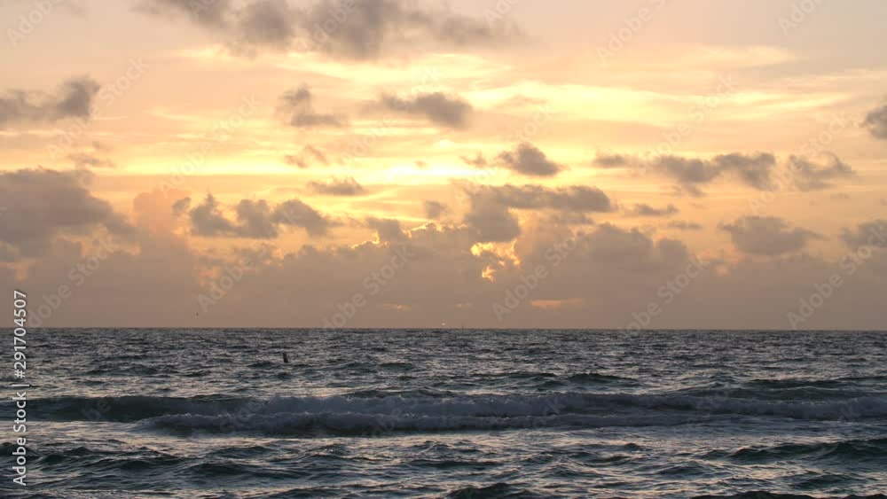 Handheld shot of the sunset from behind the clouds over the ocean Handheld shot of the sunset from behind the clouds over the ocean