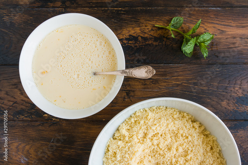 Dough making. Mixing eggs and milk in white bowl. Wooden rustic table  top view