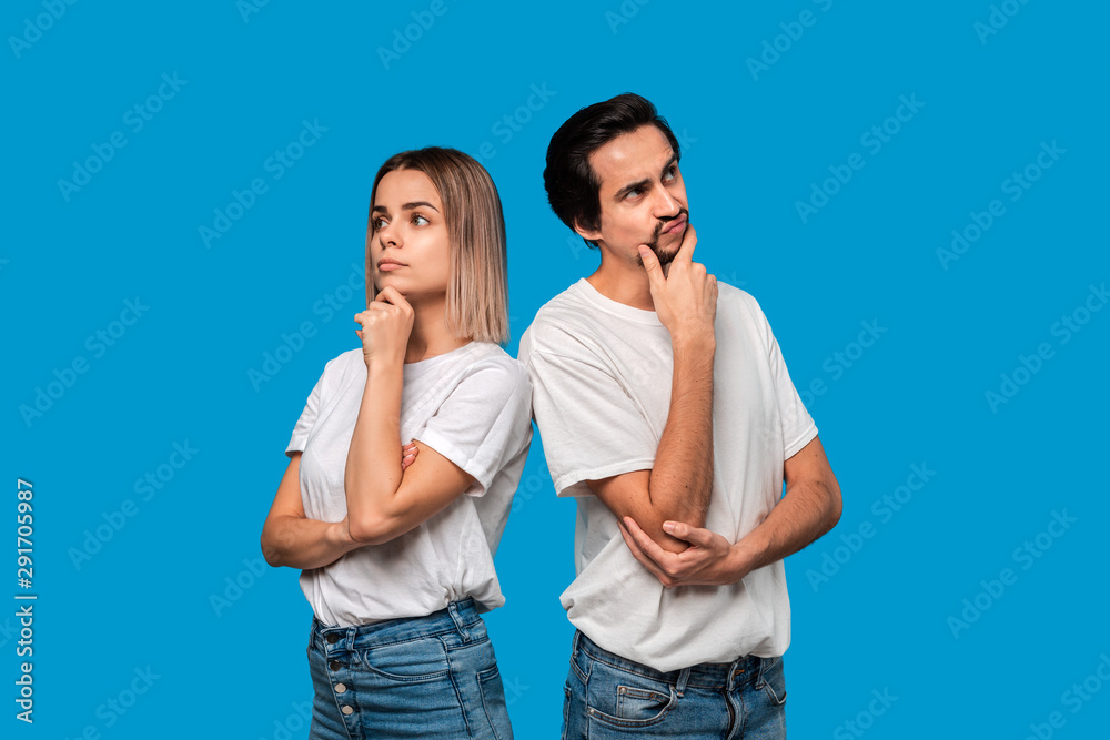 Thoughtful couple of a bearded brunet man with mustache and blond woman in white t-shirts and blue jeands standing isolated over white background. Thoughtful couple of a bearded brunet man with mustache and blond woman in white t-shirts and blue jeands standing isolated over white background.