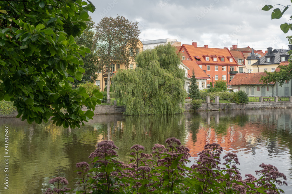 Buildings and willow in town park. Reflections. Orebro town. Background or illustration. Travel photo.