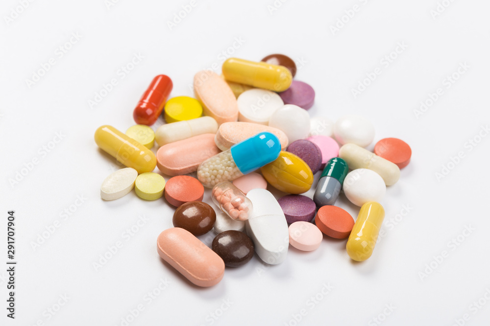 Assorted pharmaceutical medicine pills, tablets and capsules.Heap of assorted various medicine tablets and pills different colors on white background. Top view.Copy space