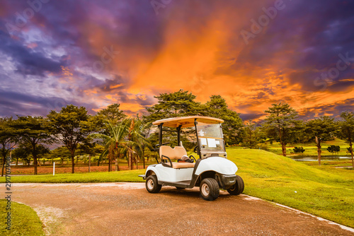A golf cart parking on road at golf course with beautiful twilight sky background, summer color style.