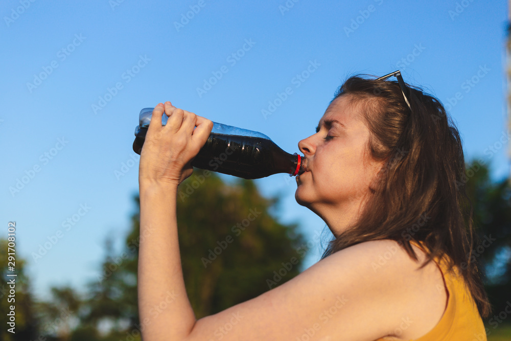 Profile shot of young woman drinking soda from plastic bottle Profile shot of young woman drinking soda from plastic bottle