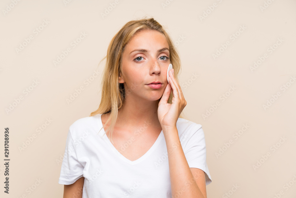 Young blonde woman removing makeup from her face with cotton pad Young blonde woman removing makeup from her face with cotton pad