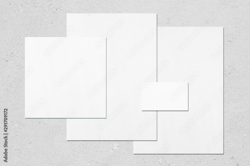 Empty white office stationery mockups with soft shadows on neutral light grey concrete background. Flat lay, top view