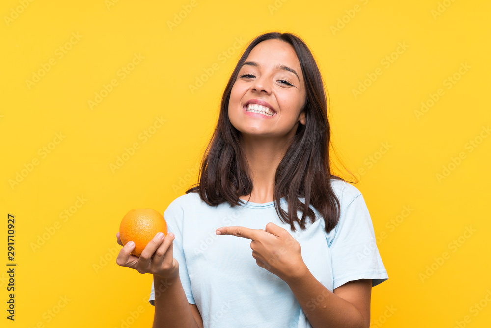 Young brunette woman holding an orange and pointing it Young brunette woman holding an orange and pointing it
