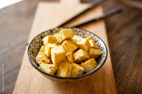 stir fry tofu with curry and sesame seeds into an oriental bowl and chopsticks
