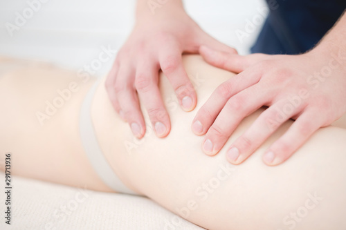 Fototapeta Naklejka Na Ścianę i Meble -  Closeup of the arm of a masseur male doing hip massage to a girl in a spa salon. Massage and body care concept