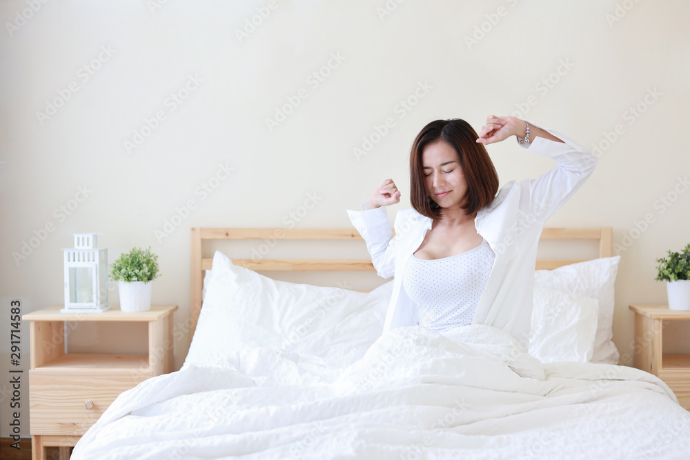 front view beautiful and healthy young asian woman wake up in the morning, she stretching after wake up in the morning on white bed in bedroom front view beautiful and healthy young asian woman wake up in the morning, she stretching after wake up in the morning on white bed in bedroom