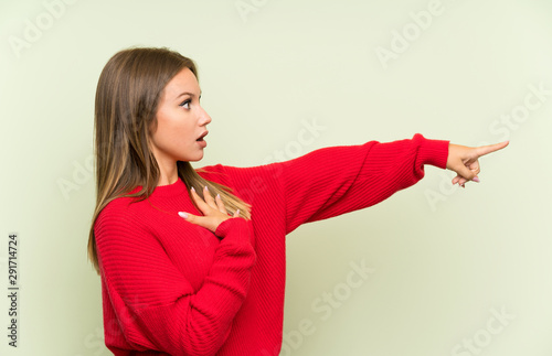 Teenager girl over isolated green background pointing finger to the side