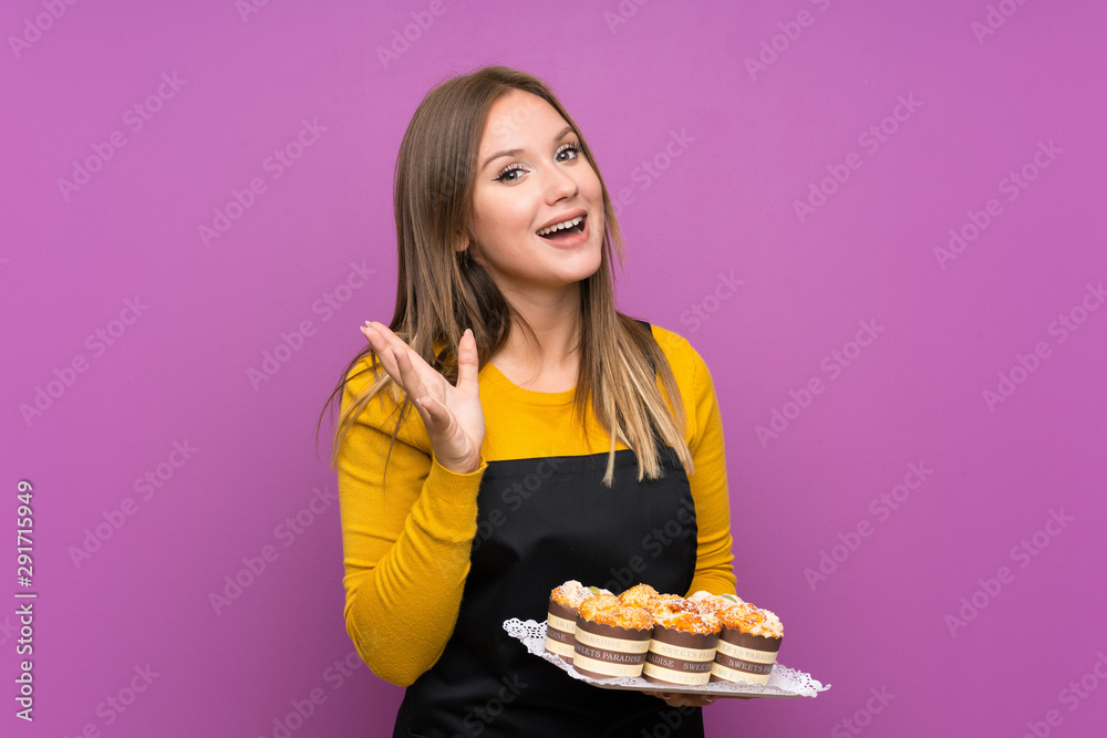 Teenager girl holding lots of different mini cakes over isolated purple background unhappy and frustrated with something Teenager girl holding lots of different mini cakes over isolated purple background unhappy and frustrated with something