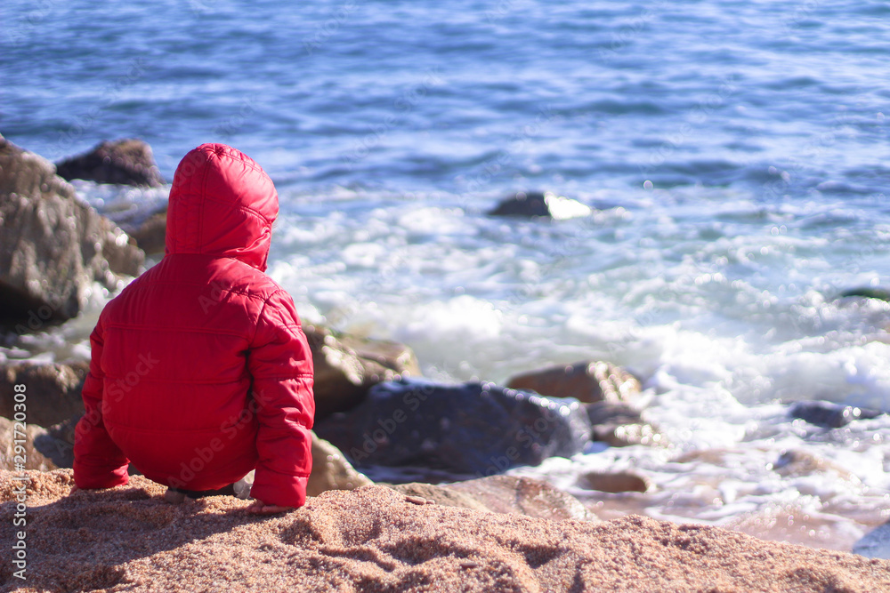 Little boy on the beach in a cold day of winter Little boy on the beach in a cold day of winter