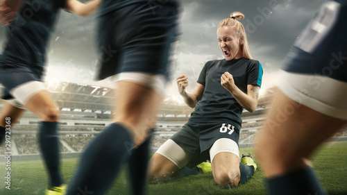 Taste or win. Young female soccer or football player in sportwear celebrating the goal in action at the stadium while gameplay. Concept of healthy lifestyle, professional sport, hobby, motion