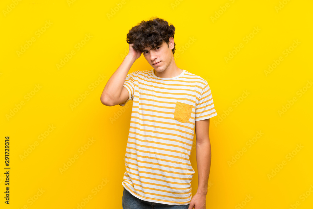 Young man over isolated yellow wall having doubts Young man over isolated yellow wall having doubts