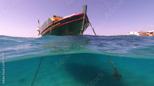 Above and below underwater photo of traditional fishing boat docked in turquoise  clear sea in port of Koufonisi island  Small Cyclades  Greece