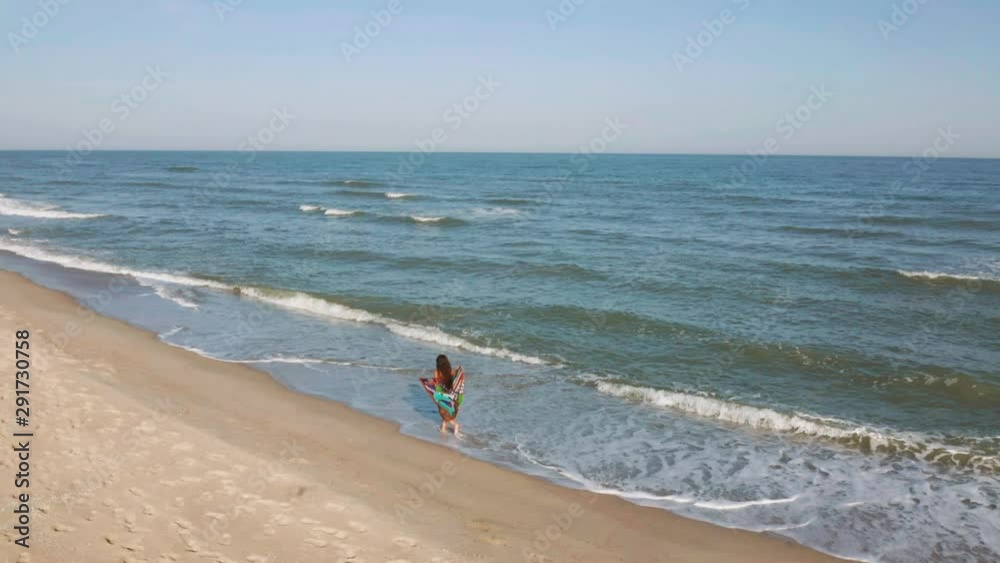 Beautiful scene of a woman walking on ocean beach at sunset Beautiful scene of a woman walking on ocean beach at sunset