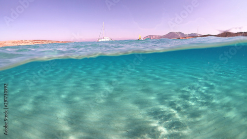 Above and below underwater photo of turquoise clear sea of Ammos sandy beach near port of Koufonisi island, Small Cyclades, Greece