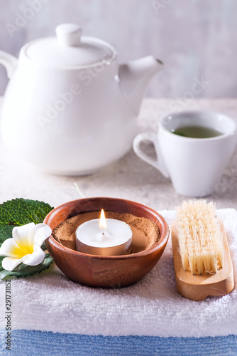Spa resort therapy composition. Burning candles, towel, tea set and flower on a stone background,