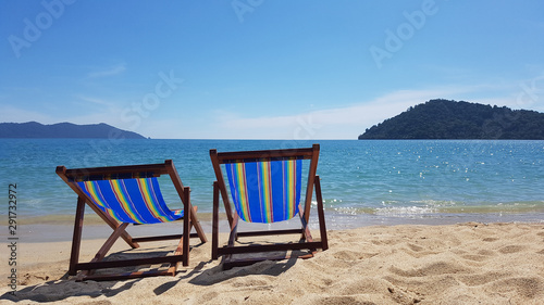 Fototapeta Naklejka Na Ścianę i Meble -  Two colorful empty beach chairs on the beach near the water