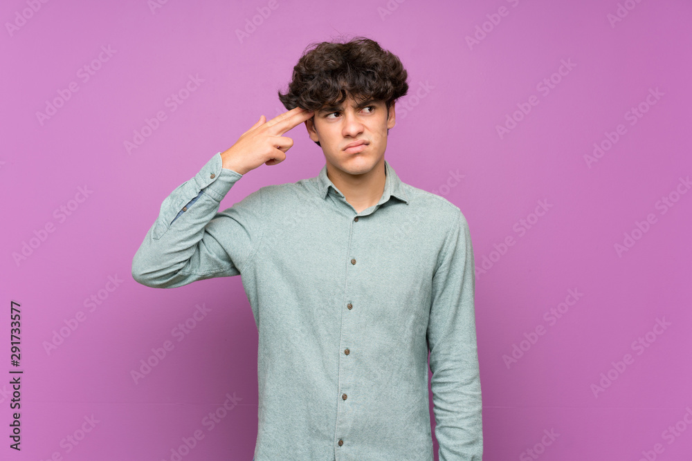 Young man over isolated purple wall with problems making suicide gesture Young man over isolated purple wall with problems making suicide gesture