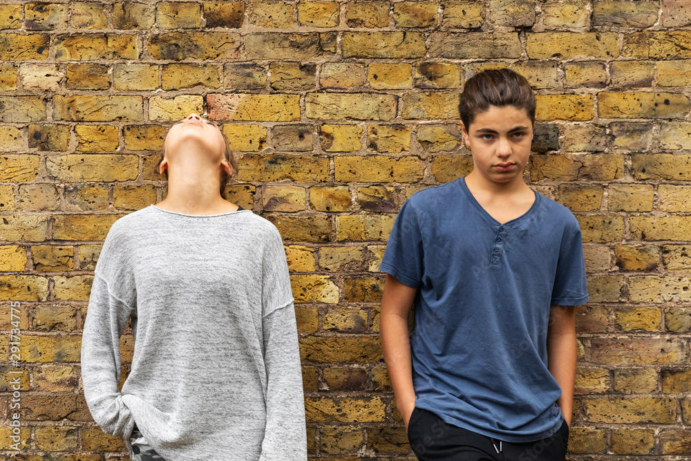 Two depressed young teens stand in front of a brick wall Two depressed young teens stand in front of a brick wall